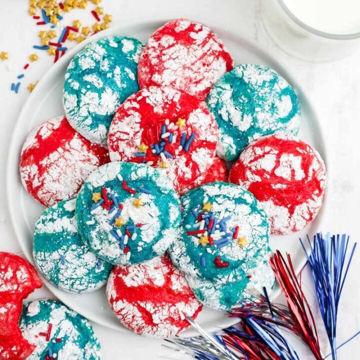 Overhead of red, white, and blue cookies served on a white platter with festive decorations around.