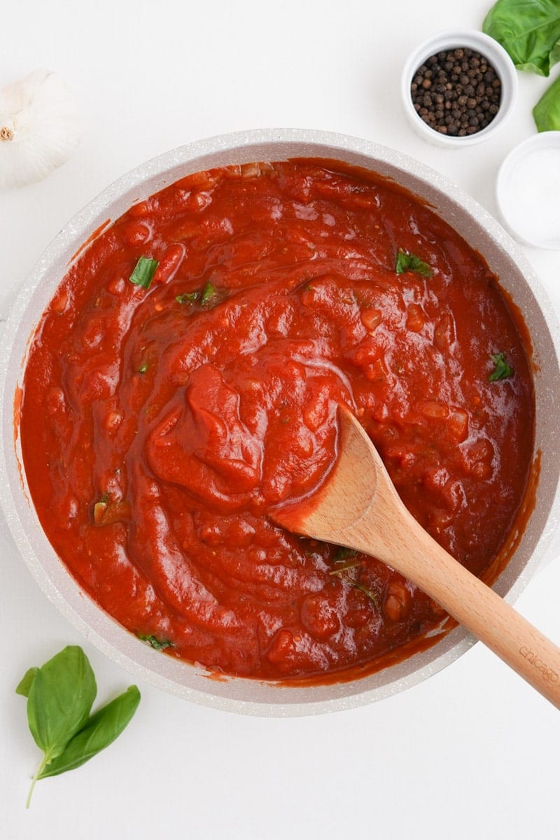 A spoon scoops into a bowl of arrabbiata sauce.