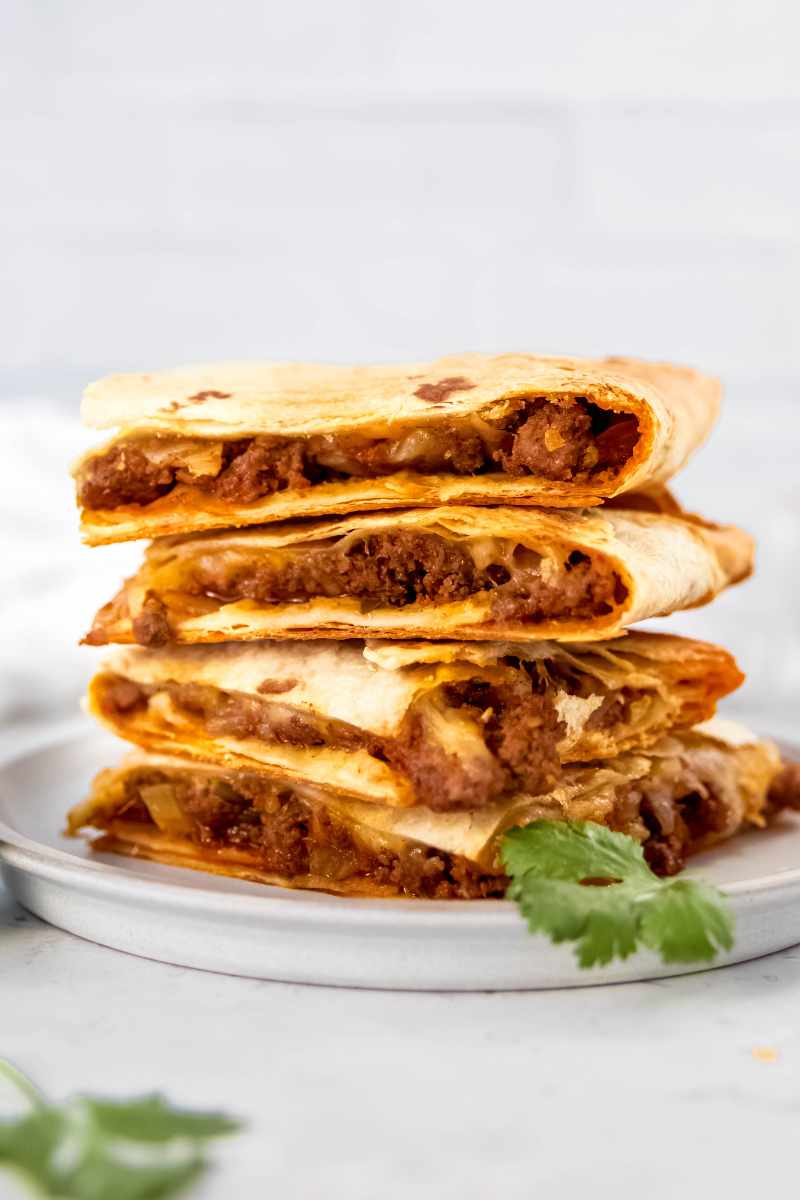 Ground beef quesadillas stacked on a white plate.