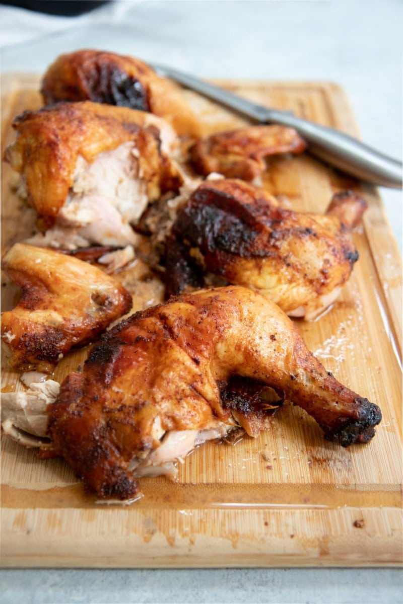 Side angle shot of cut-up grilled chicken on a wooden cutting board