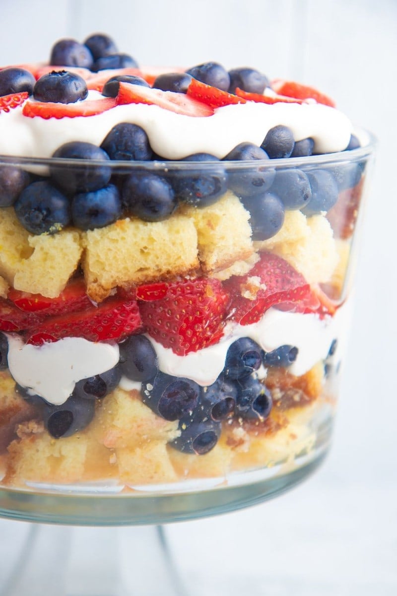 Close view of the layers of cake, blueberries, strawberries, and cream cheese whipped cream in a festive berry trifle.