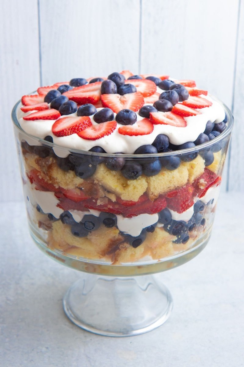 A berry trifle served in a glass trifle dish showing the layers of cake, berries, and cream.