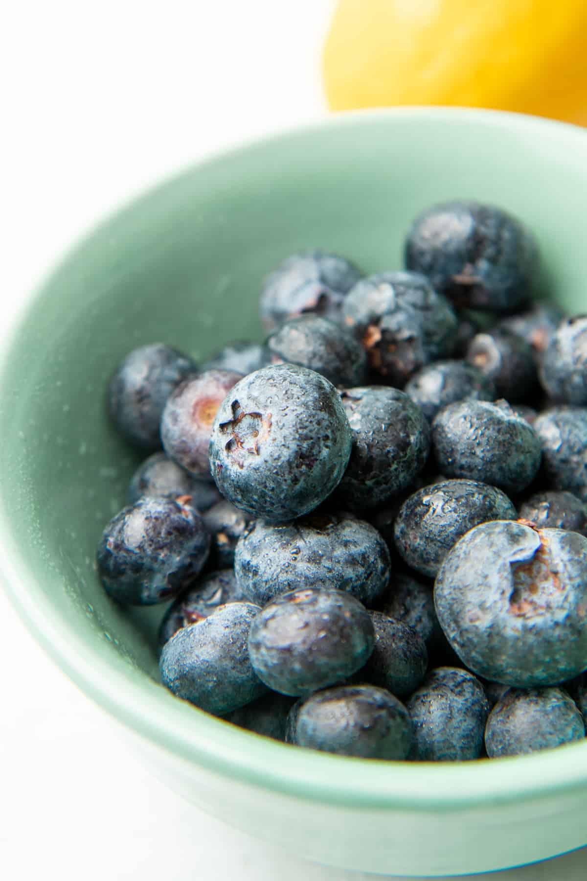 Blueberries sit in a teal bowl.