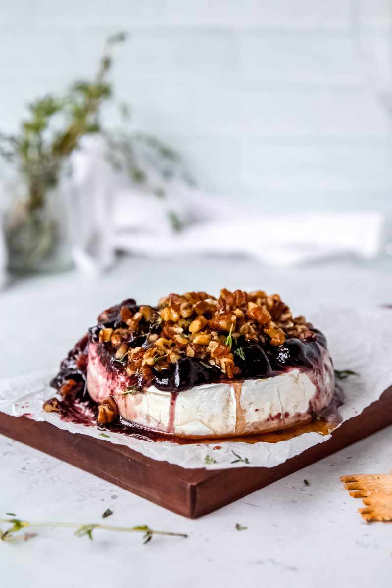 And easy brie holiday appetizer on a parchment paper lined serving board, fresh thyme in the background.