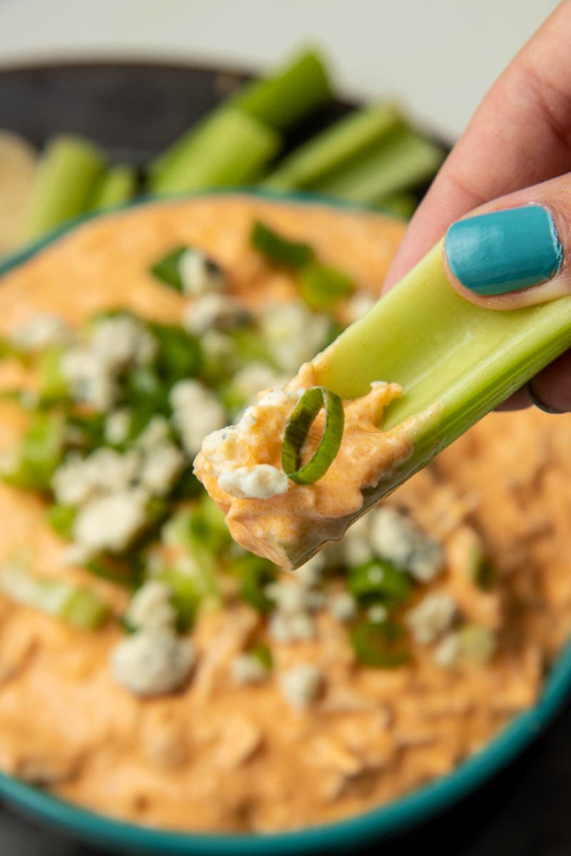 Close view of a bite of Instant Pot chicken dip on a celery stick.