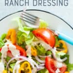 A white bowl is filled with a colorful salad dressed with paleo cashew ranch dressing. A text overlay reads "Dairy-Free Ranch Dressing."