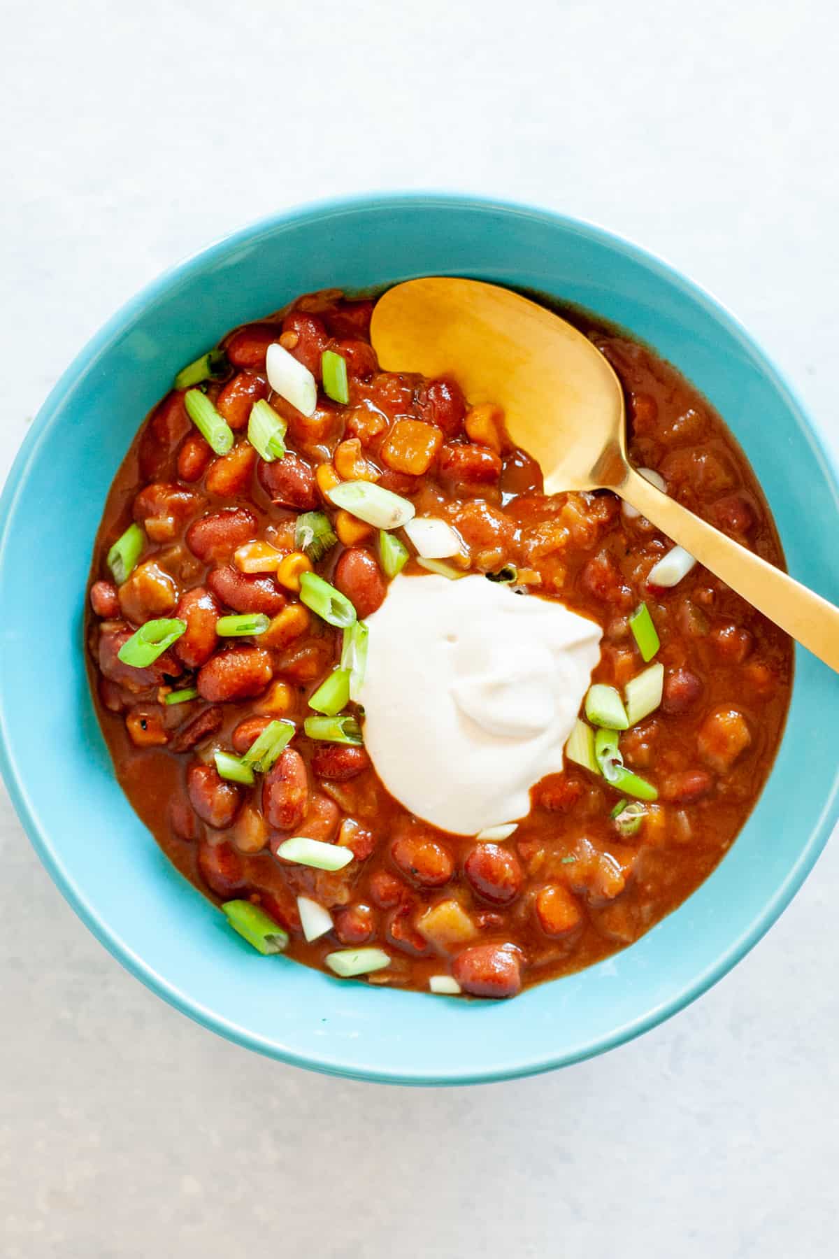 Sour cream made from cashews on top of chili in a blue bowl.