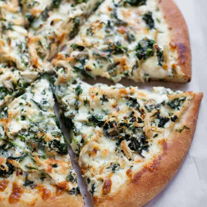 Overhead shot of Chicken Spinach Alfredo Pizza, cut into slices