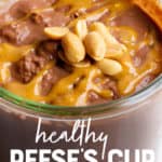 Close up of peanut butter chocolate overnight oats in a glass jar. There are peanuts garnishing the top, and a spoon dips into the jar. A text overlay reads "Healthy Reese's Cup Overnight Oats."