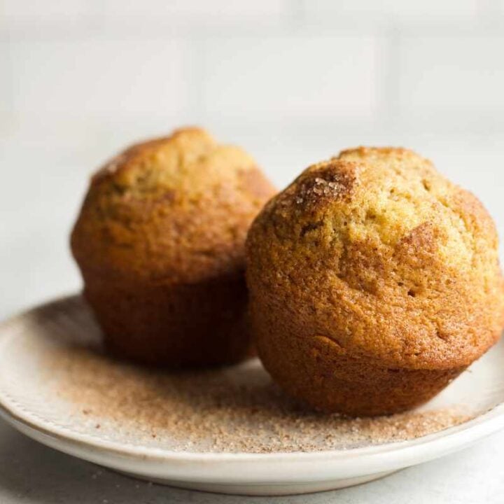 Close view of two cinnamon muffins on a small serving plate.