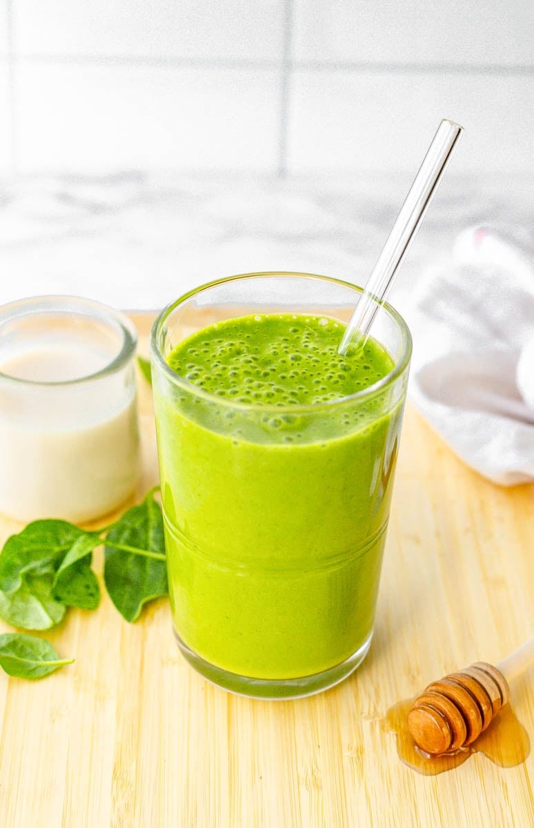 Finished smoothie on a cutting board with fresh ingredients around it.