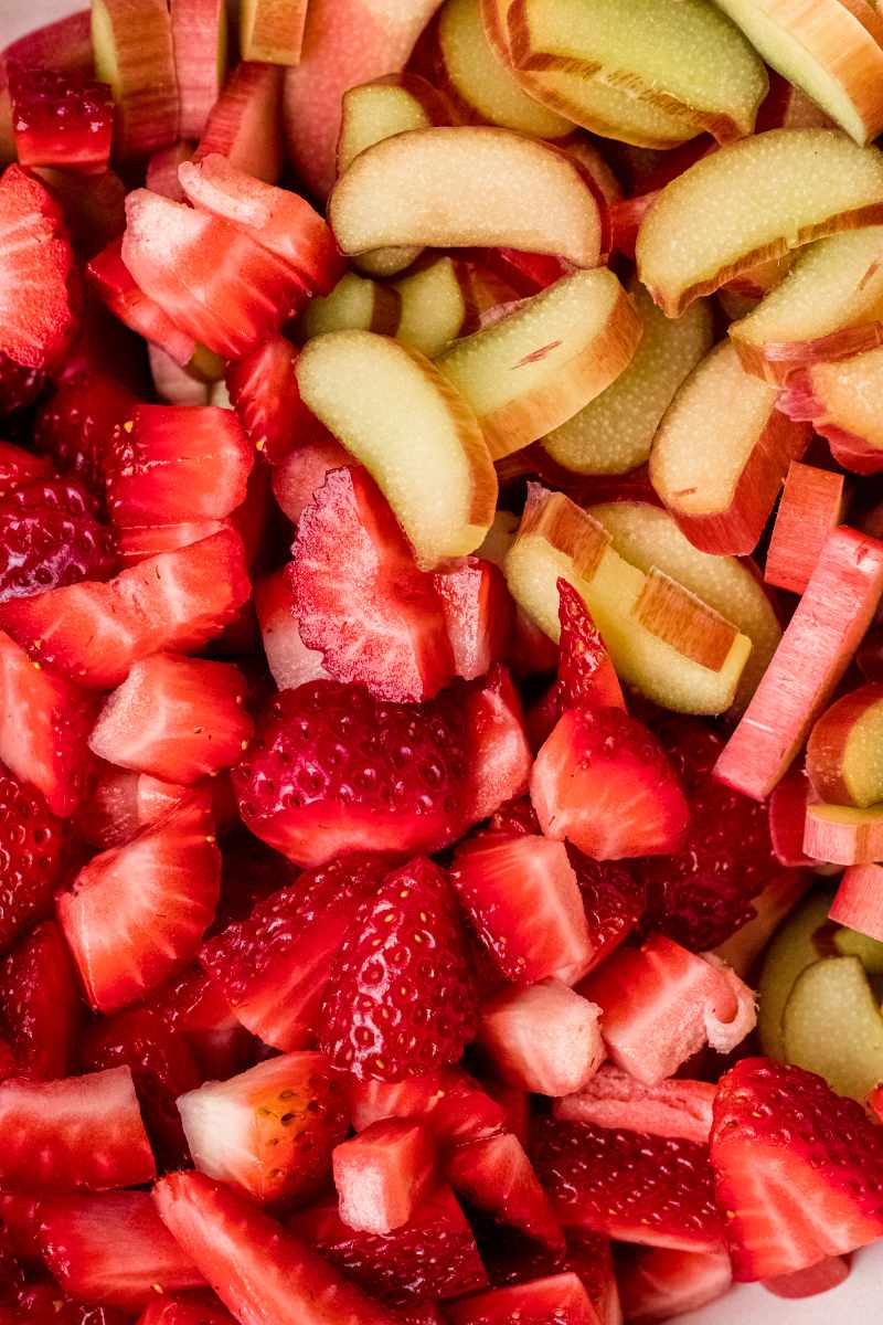 Close view of fresh cut strawberries and rhubarb in one pile side by side.