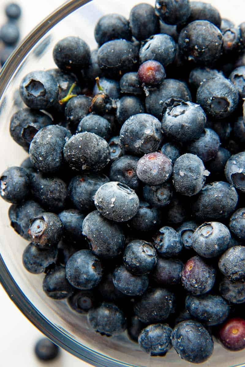 Close-up of individually frozen blueberries in a glass container.