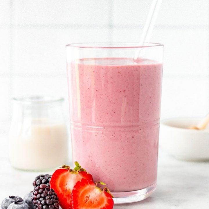 Close up of mixed berry smoothie with fresh berries beside it.