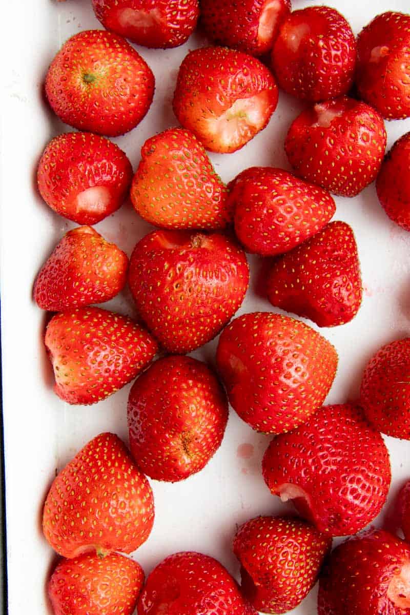 Close-up of fresh strawberries cleaned and hulled on a baking tray.