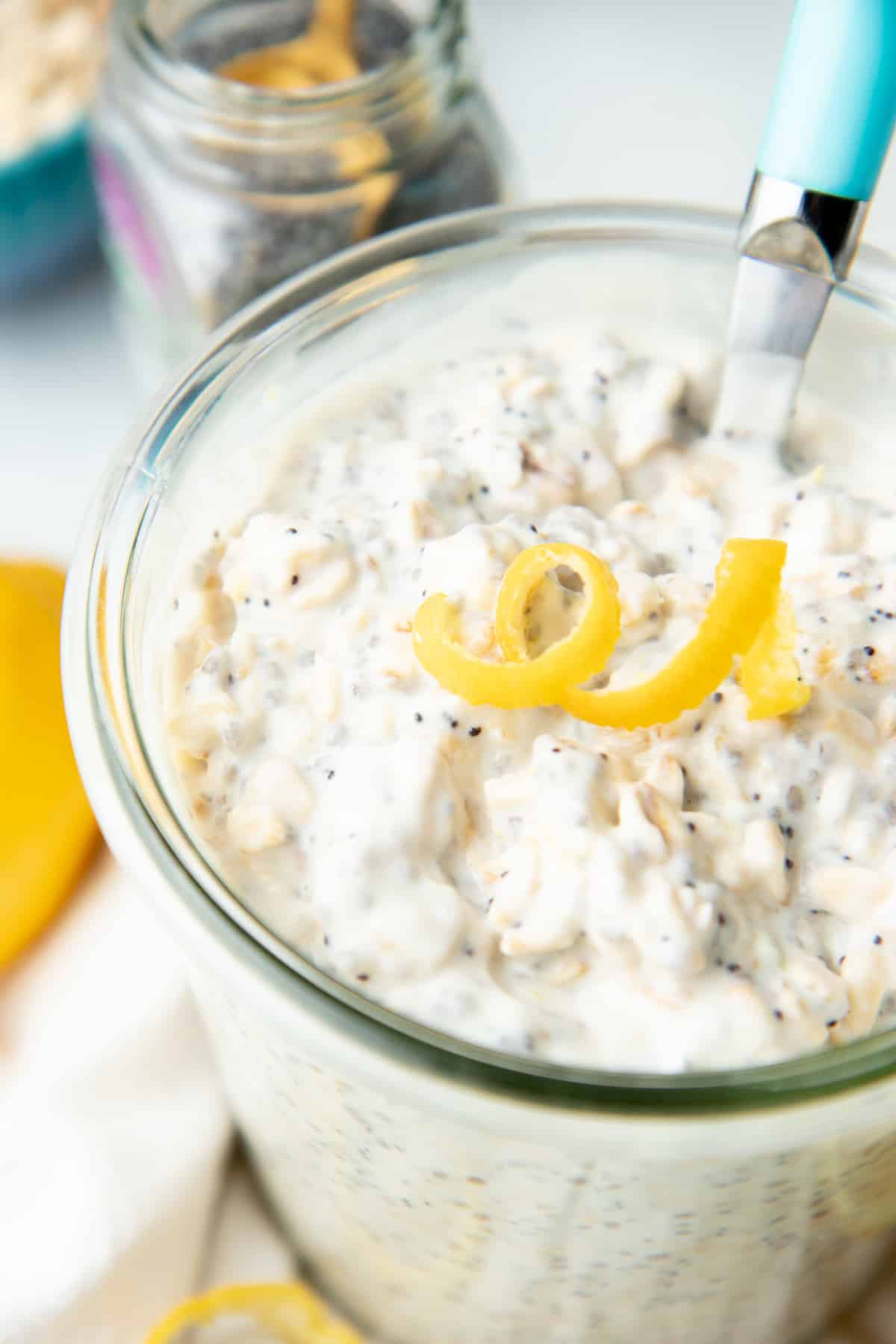 A jar is filled with lemon poppyseed overnight oats. It is topped with a twirl of lemon zest.