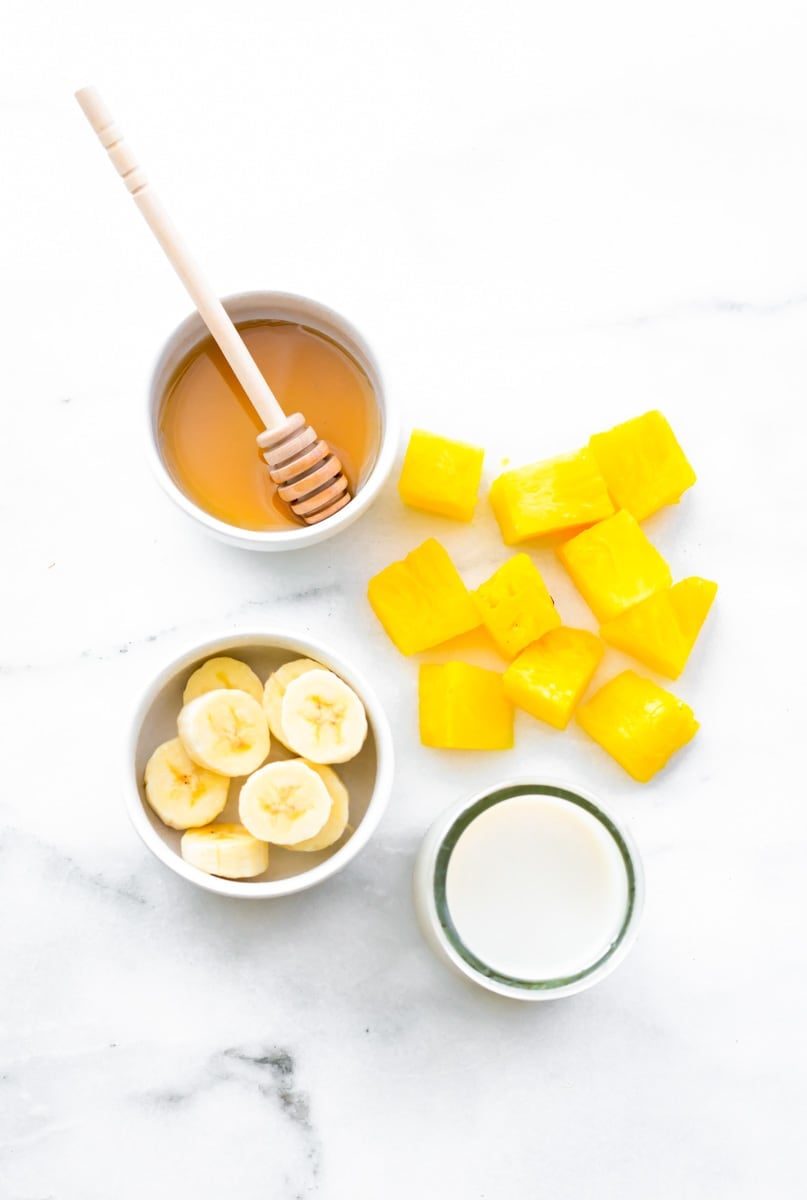 Overhead of four ingredients needed for coconut pineapple smoothie recipe.