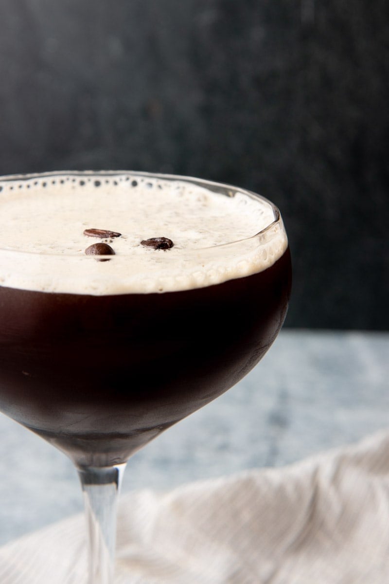 Close view of a chilled coffee cocktail in a stemmed glass on a dark background.