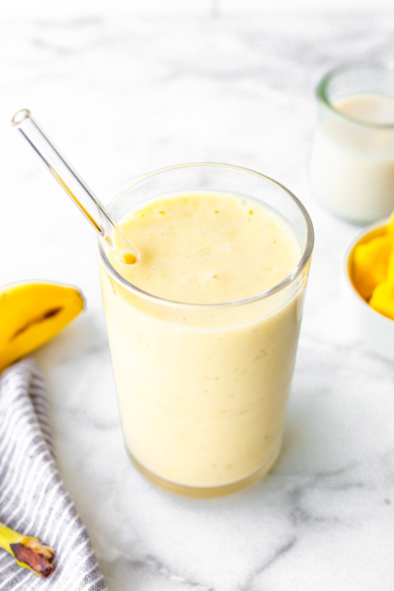 Overhead of pineapple coconut smoothie with a glass straw.