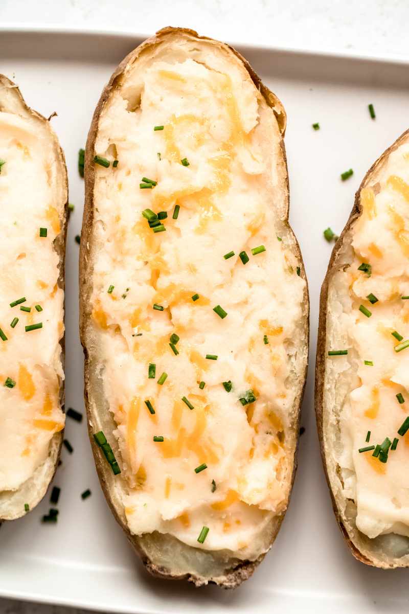 Top view of double baked potatoes garnished with chives on a white plate.