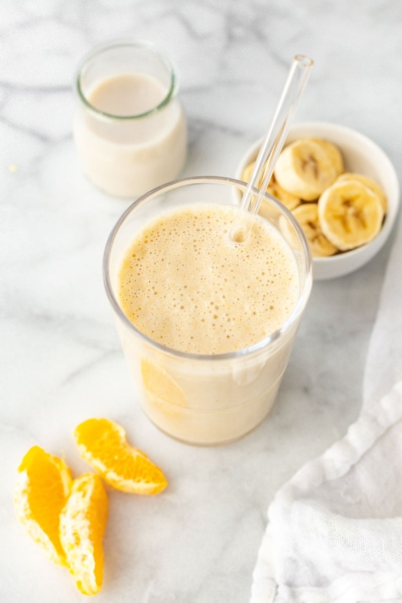 Overhead of creamsicle smoothie with orange segments and banana slices.