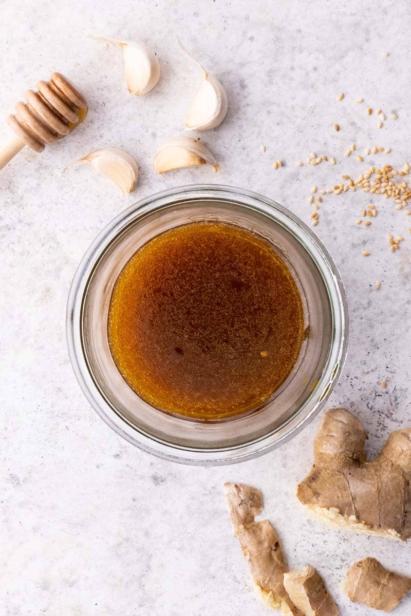 Finished salad dressing mixed in a bowl, with fresh ingredients around it.