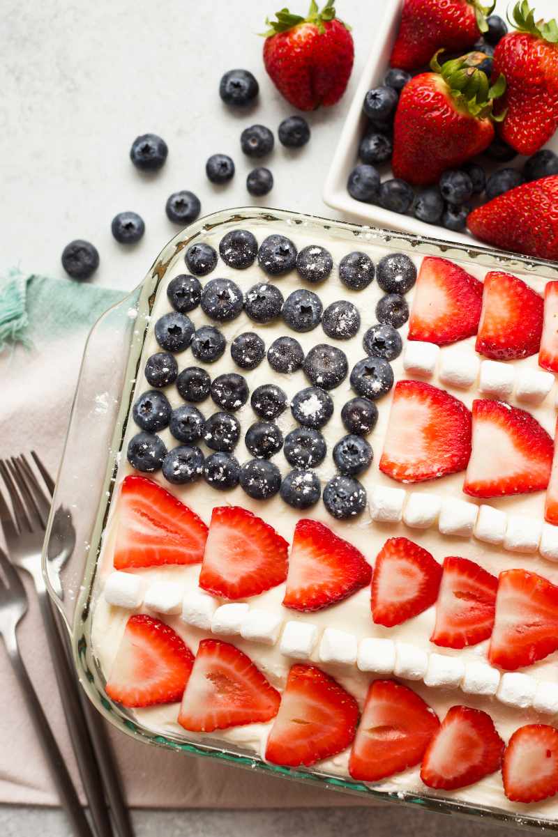 Overhead of fresh blueberries and strawberries decorating the top of a cake to look like a patriotic flag.