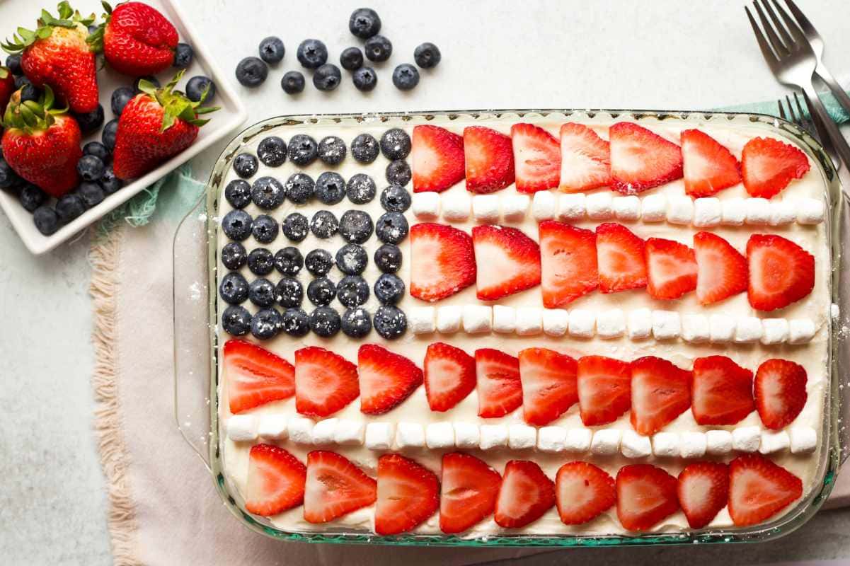 Forks rest alongside a glass baking dish with a cake decorated to look like the American flag.