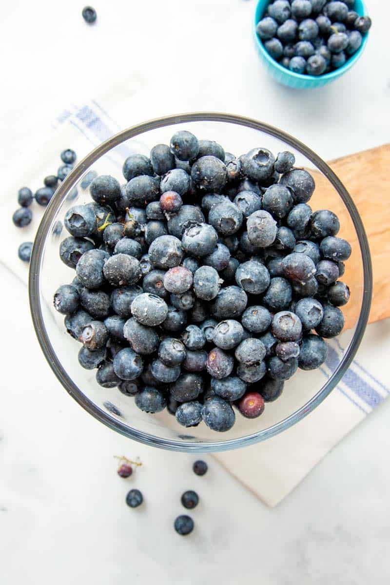 Overhead of individually frozen blueberries in a glass bowl.