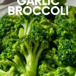 Steamed garlic broccoli served on a white plate with a linen tablecloth beneath. A text overlay reads, "The Easiest Garlic Broccoli."