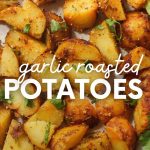 Garlic roasted potatoes garnished with chopped flatleaf parsley. A text overlay reads, "Garlic Roasted Potatoes."