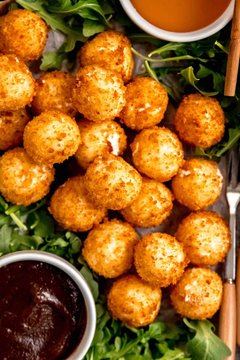 A pile of crispy coated goat cheese balls served alongside honey and jam.