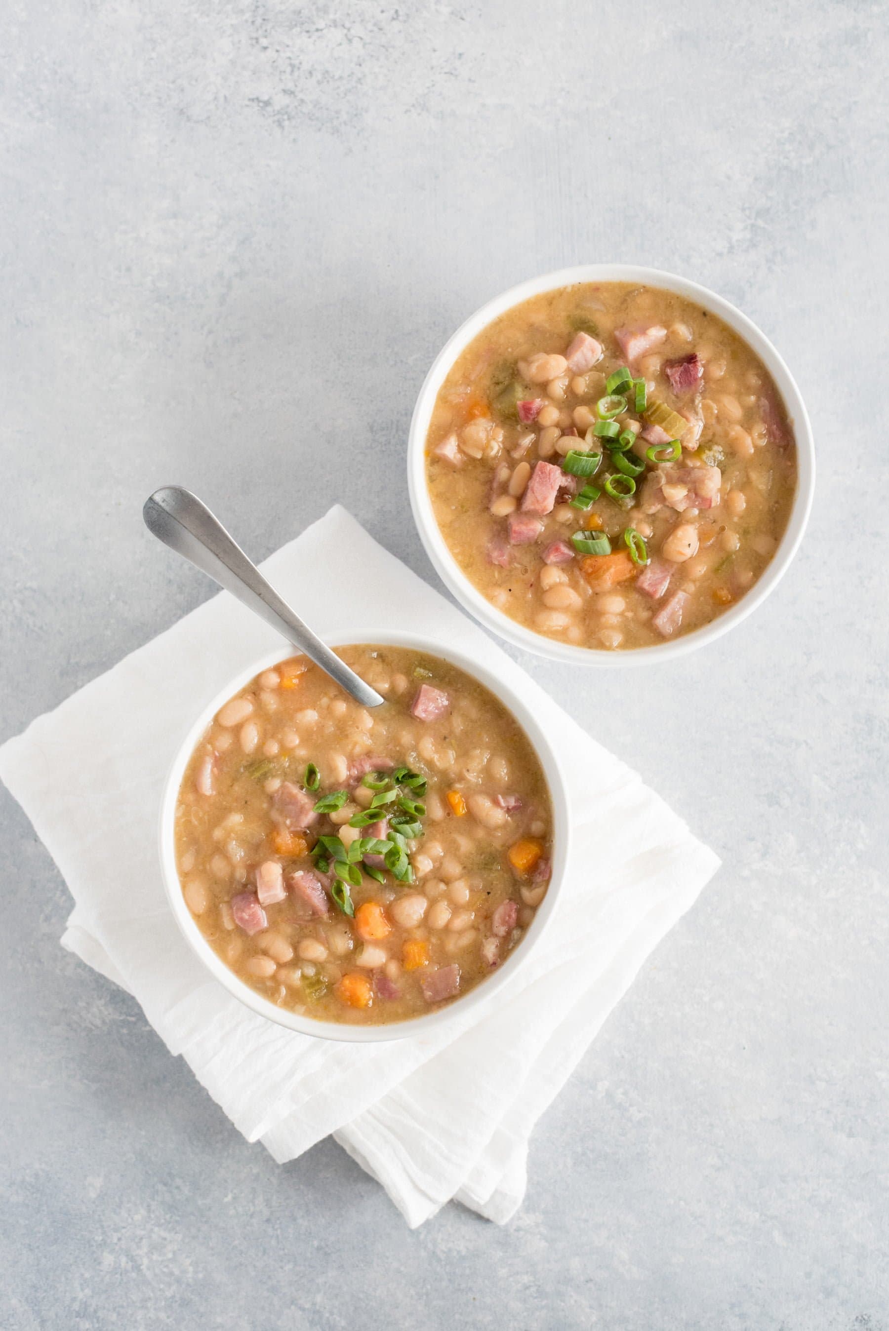 Overhead of two bowls of ham and bean soup on a counter.