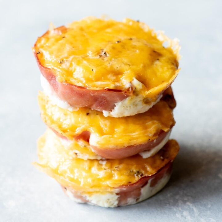 Close view of three ham and egg cups stacked on a light background.