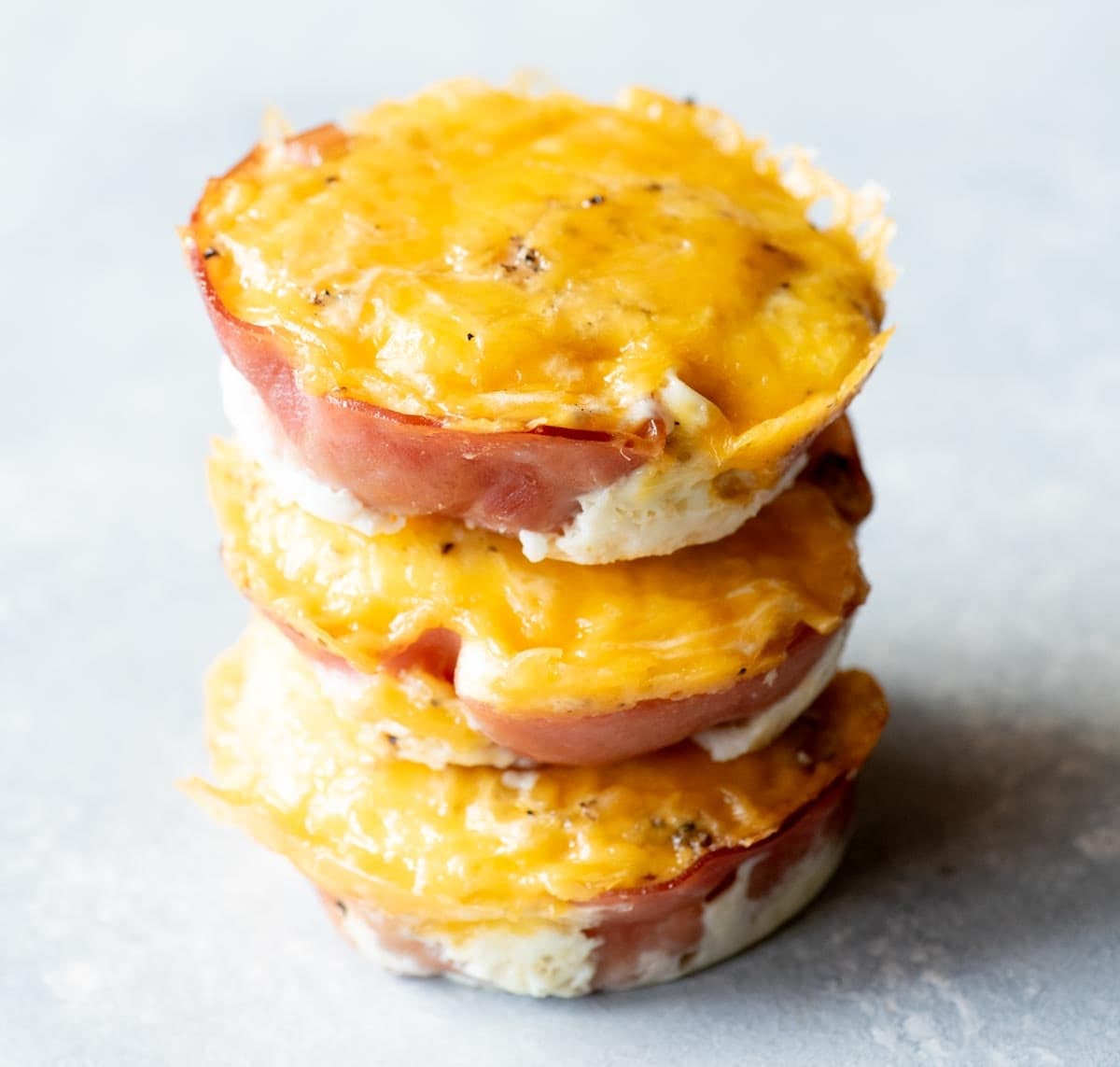 Close view of three ham and egg cups stacked on a light background.