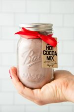 A jar of homemade hot chocolate mix held up in the palm of a hand.