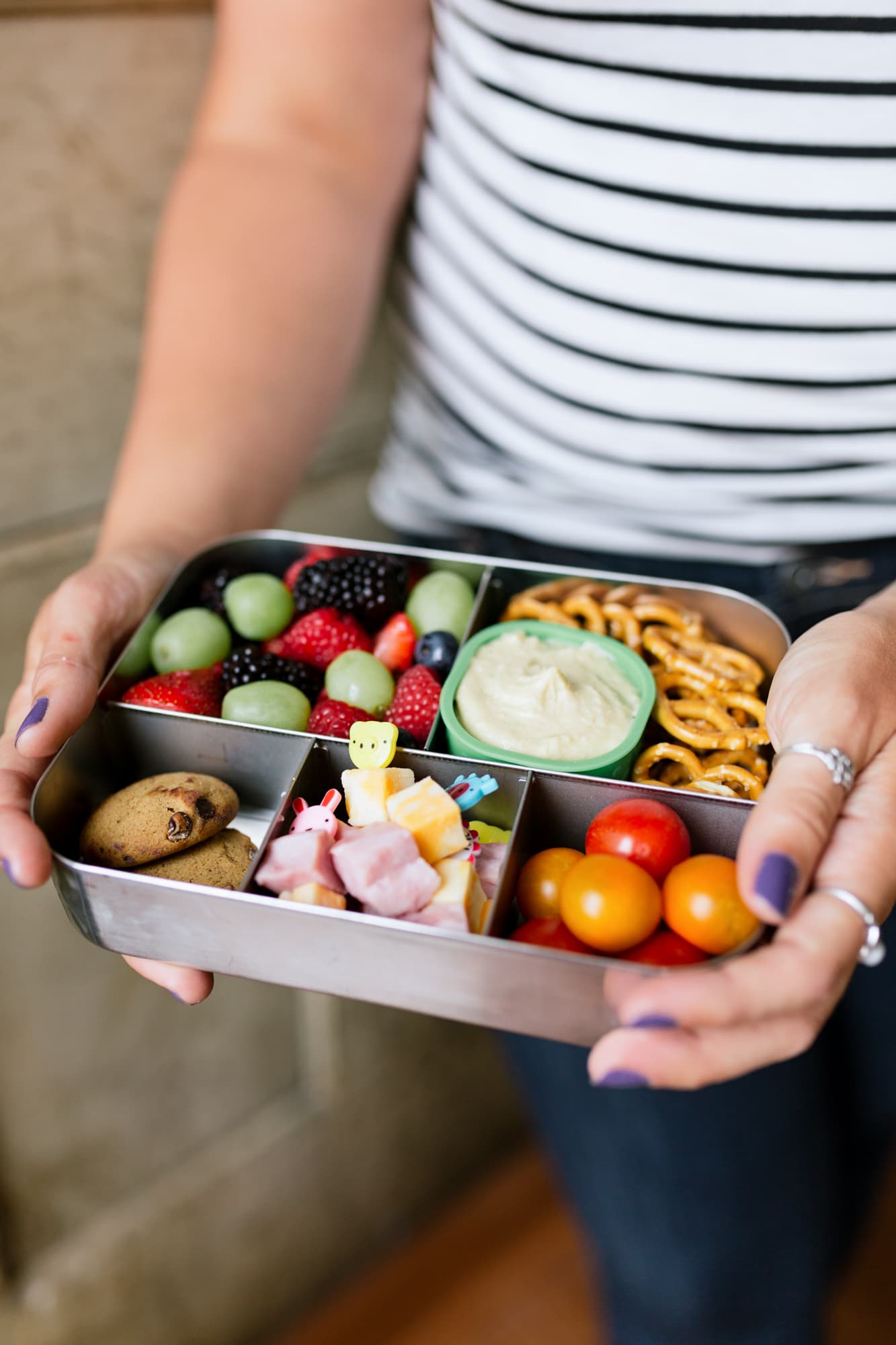 Hands holding a filled bento-style lunch box for a zero-waste lunch