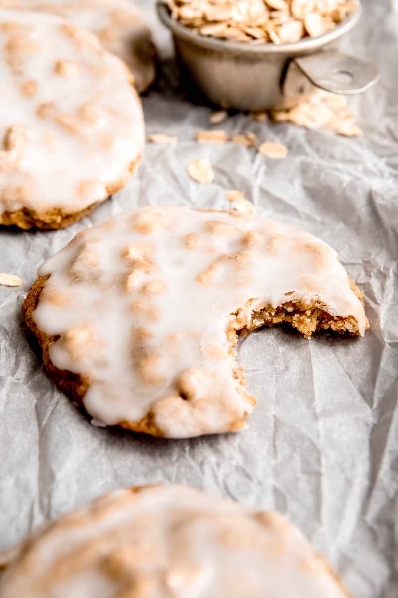 Tight view of an iced oatmeal cookie with a bite taken out of it.