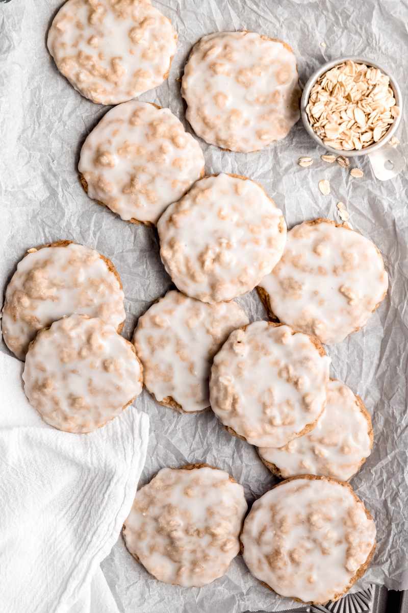 Top view of iced oatmeal cookies on a parchment paper lined serving tray.