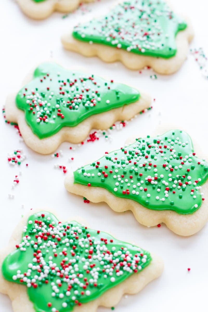 Decorated Christmas tree sugar cookies with green frosting rest on a white background.