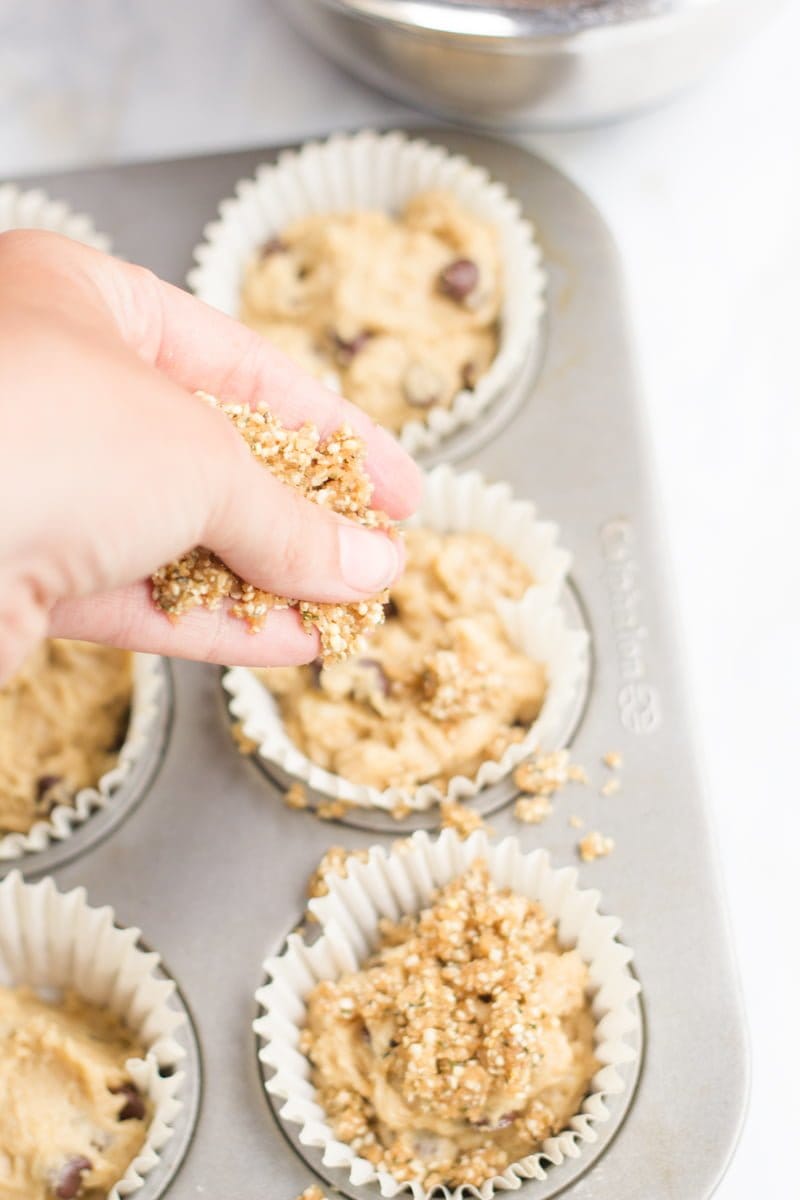 A hand pours hemp seed streusel on top of the Whole Wheat Banana Muffin dough