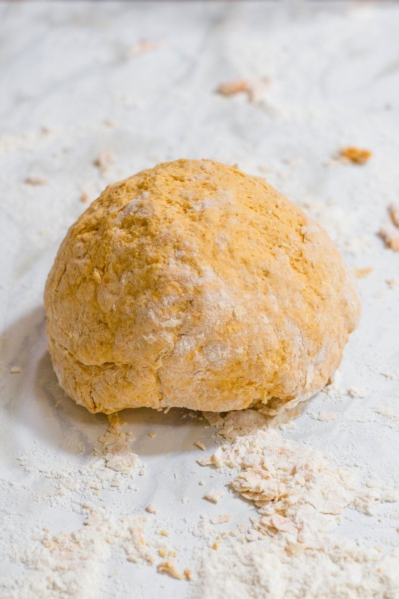 An orange ball of pasta dough, ready to be rolled and cut.