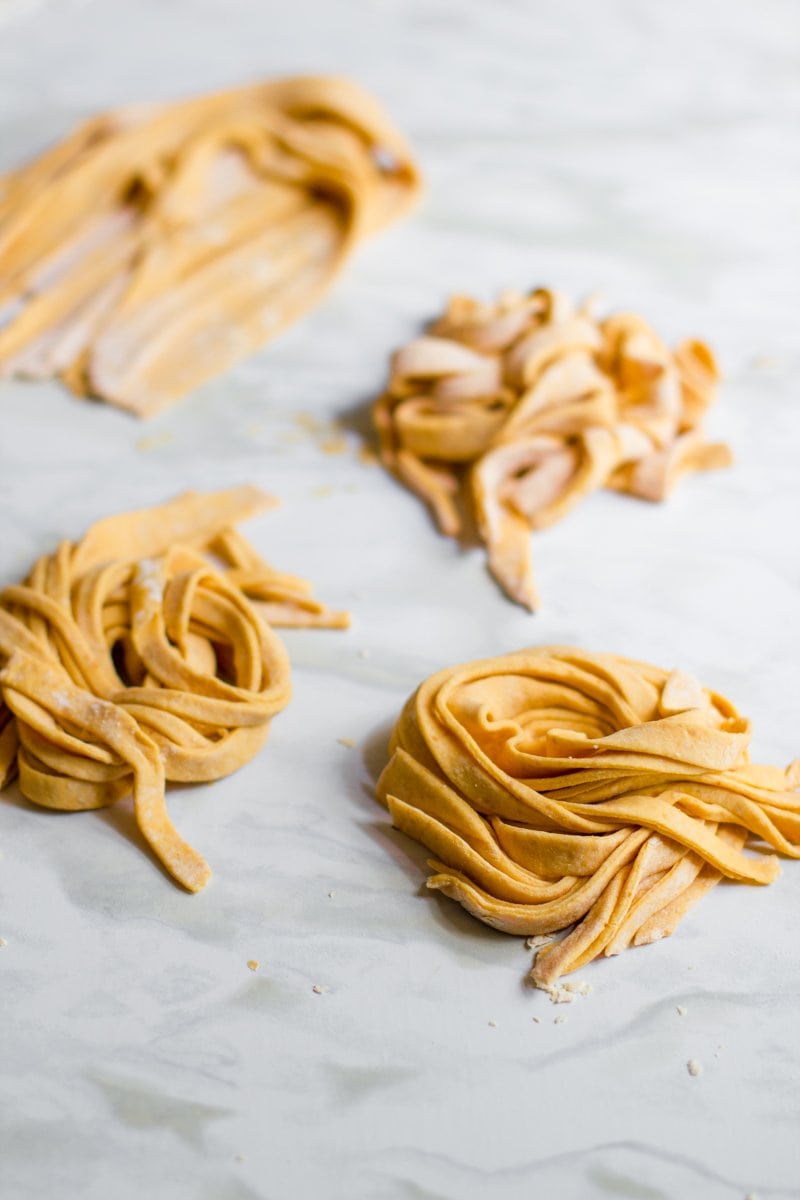 Bundles of pumpkin pasta rest on a marble counter.