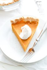 Overhead of a slice of sweet potato pie on a stack of plates with a fork.