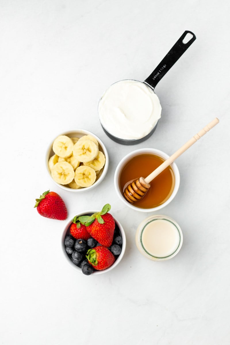 Overhead of five ingredients needed for berry smoothie recipe.