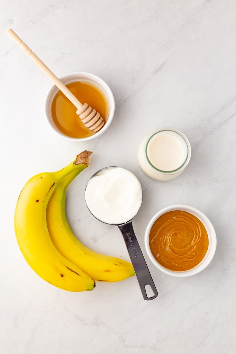 Overhead of the five ingredients needed to make a peanut butter banana smoothie.