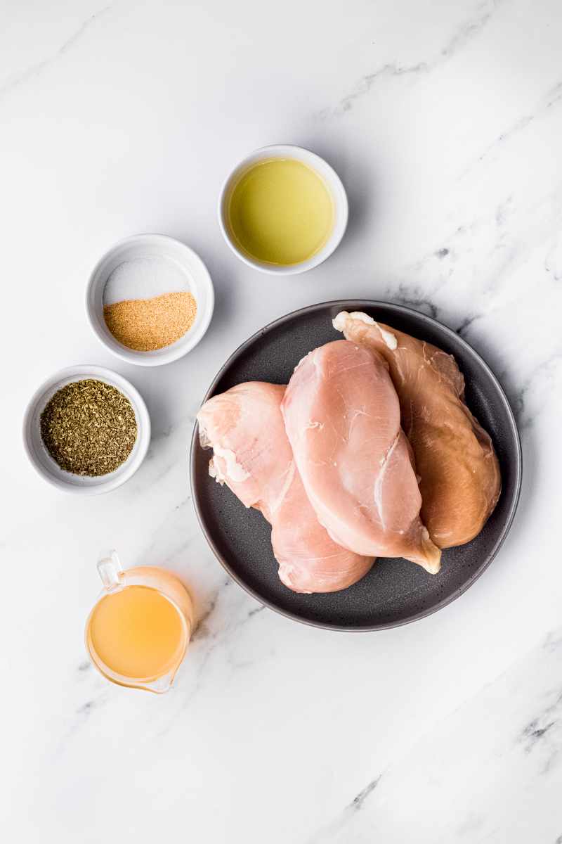 Overhead of ingredients needed to make instant pot chicken breasts including chicken and seasonings.