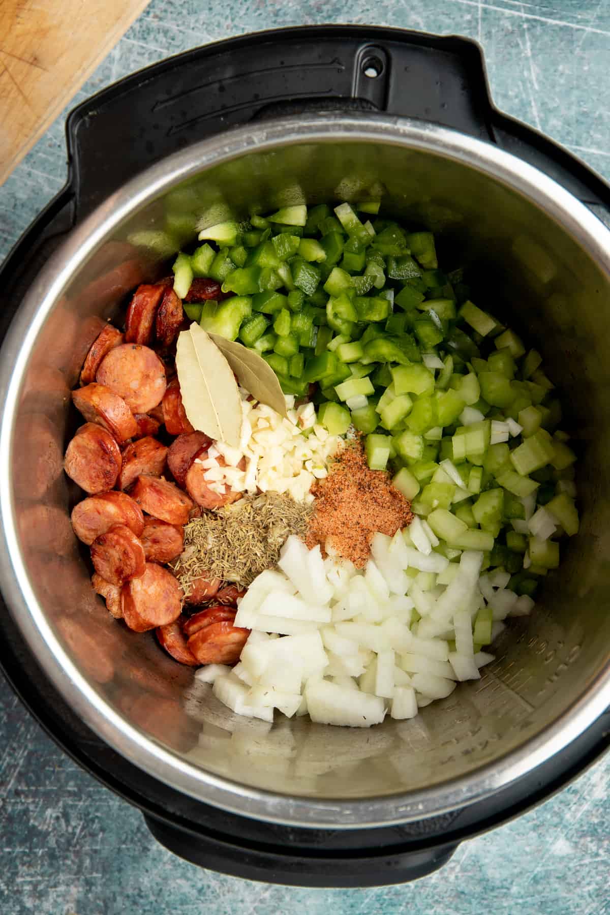 Peppers, celery, onion, sausage, bay leaves, garlic, and spices prepped in an Instant Pot.