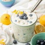 A spoon rests in a glass jar of blueberry overnight oatmeal.