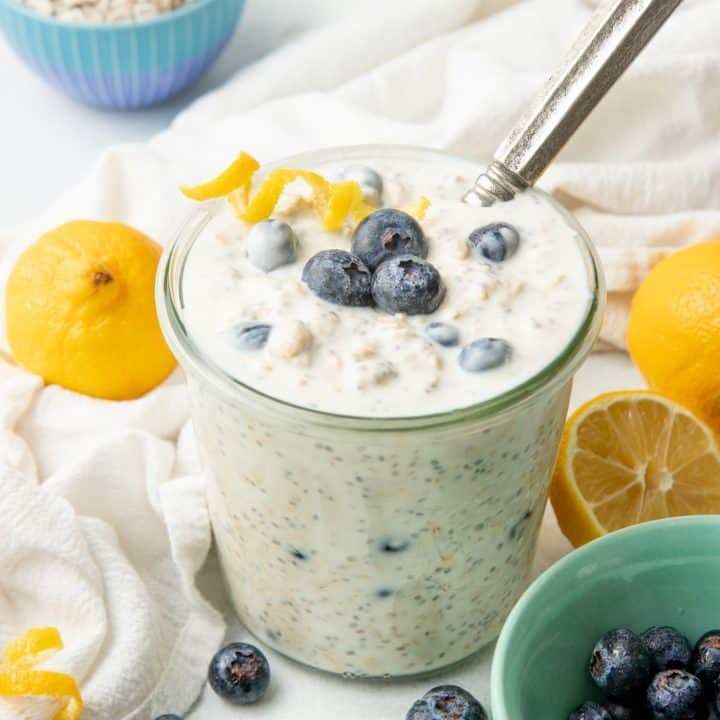 A spoon rests in a glass jar of blueberry overnight oatmeal.